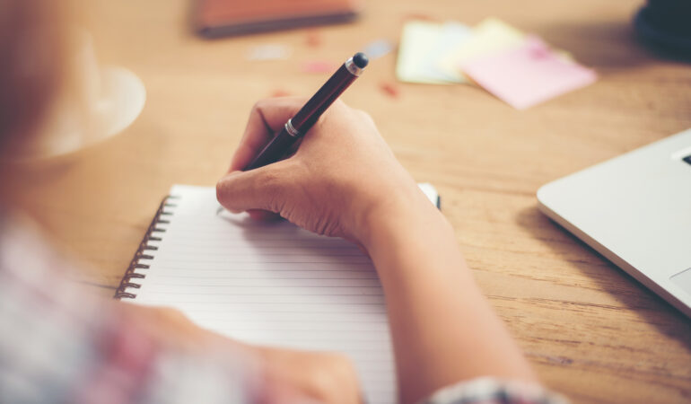 Young hipster woman writing and work in workplace.