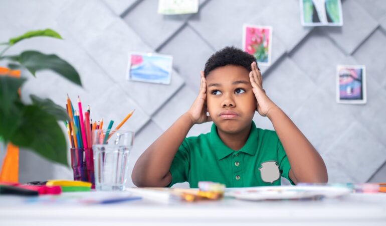 Boy touching head with hands looking pensively aside